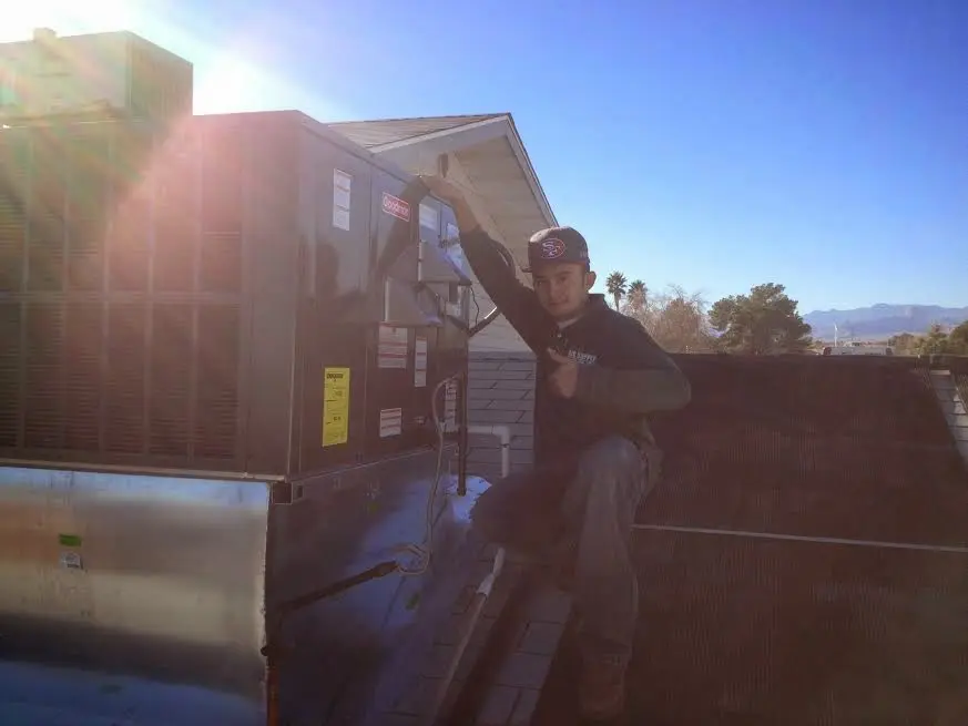 HVAC technician performing AC Tune-Up on a rooftop unit in Massanetta Springs