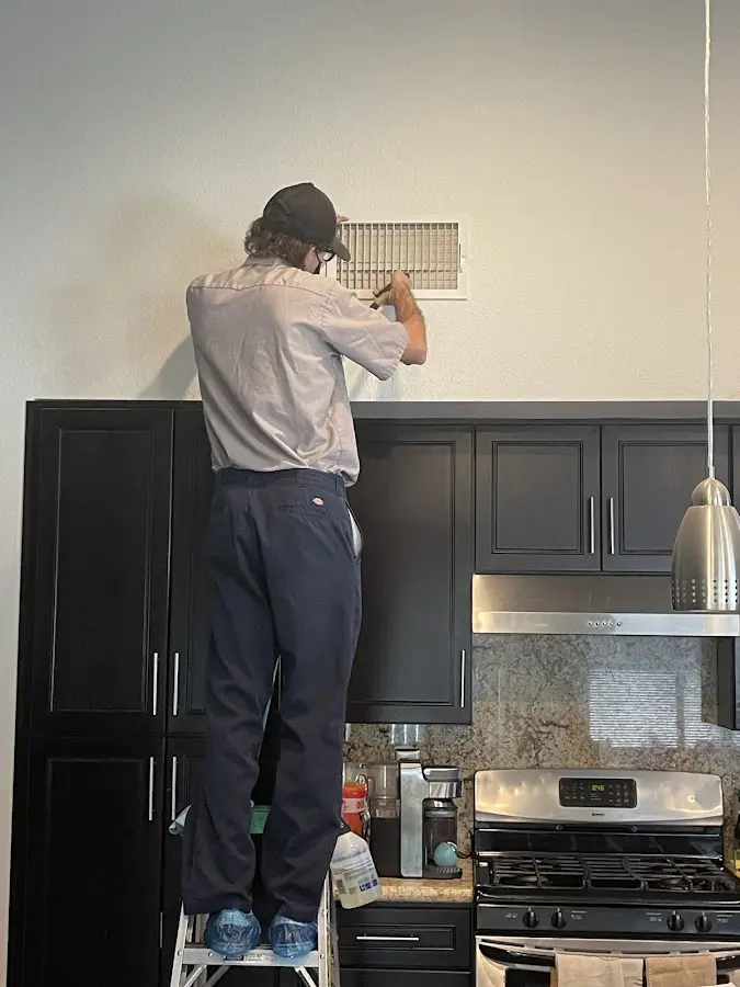 Technician inspecting an air vent during HVAC service in Massanetta Springs